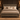 A rustic gray wooden bed frame with a high panel headboard and footboard, styled with beige and brown bedding, shams, and a textured throw blanket, set in a dark wood bedroom with matching nightstands and wall sconces.