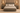 A rustic gray-brown wooden bed frame with a matching headboard and footboard, styled with neutral beige and white bedding, set in a symmetrical bedroom with matching nightstands and wall sconces.